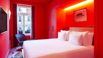 A hotel room with a bed, a chair, a desk, and a window with curtains.