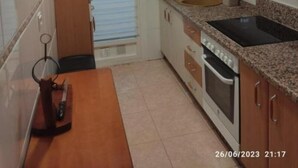 A compact kitchen with wooden cabinets, a built-in oven, and a granite countertop. - Apartamento Villa Inés (Huércal de Almería)