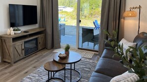 A modern living room with a flat-screen TV, wooden entertainment unit, and a sofa. - Drift Inn Duplex B - with hot tub (Ocean Shores)