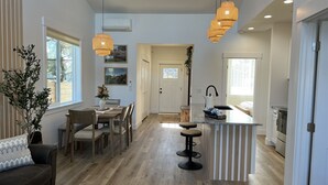 A modern kitchen with a central island, a dining area with wooden furniture, and a living room with a sofa and a coffee table. - Drift Inn Duplex B - with hot tub (Ocean Shores)