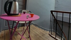Ein kleiner Raum mit einem rosa Tisch, einem Wasserkocher und einer Tasse.