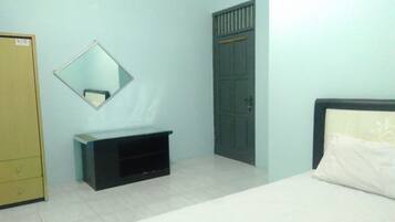 Una habitación con cama, armario, espejo y un pequeño mueble negro.