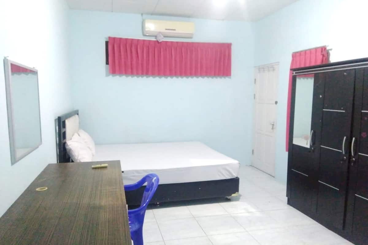 Un dormitorio con cama, escritorio, silla, armario y unidad de aire acondicionado.