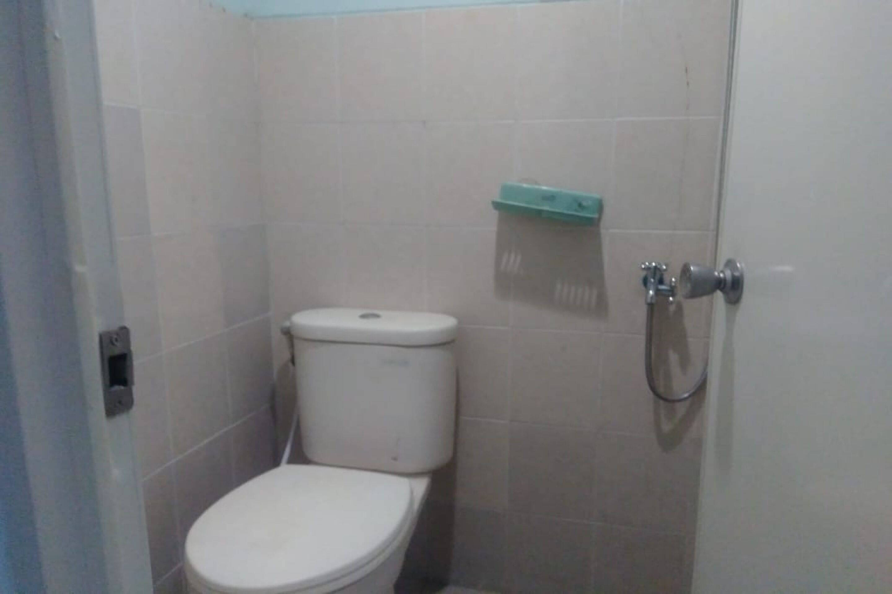 Ein kleines, abgeschlossenes Badezimmer mit Toilette, Dusche und Toilettenpapierhalter.