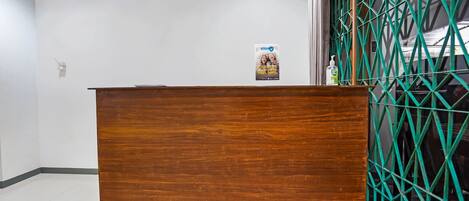 A wooden reception desk with a poster on the wall behind it.
