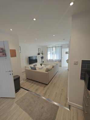 Un salon moderne avec un canapé, un téléviseur et une petite table.