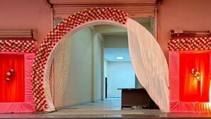 A hallway with a floral archway leading to a room with a red curtain backdrop. - Namastay Hotel (Gaya)