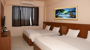 A hotel room with two beds, a wooden headboard, a painting of a landscape, a window with curtains, and a television on a wooden desk. - Namastay Hotel (Gaya)