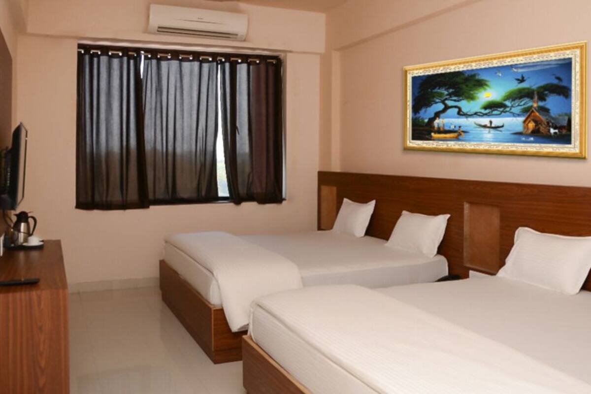 A hotel room with two beds, a wooden headboard, a painting of a landscape, a window with curtains, and a television on a wooden desk.