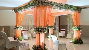A tented wedding setup with draped curtains, floral arrangements, and chairs. - Namastay Hotel (Gaya)