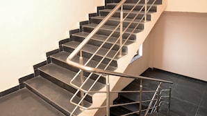 A black and beige staircase with metal handrails and a metal safety rail on the landing. - Namastay Hotel (Gaya)