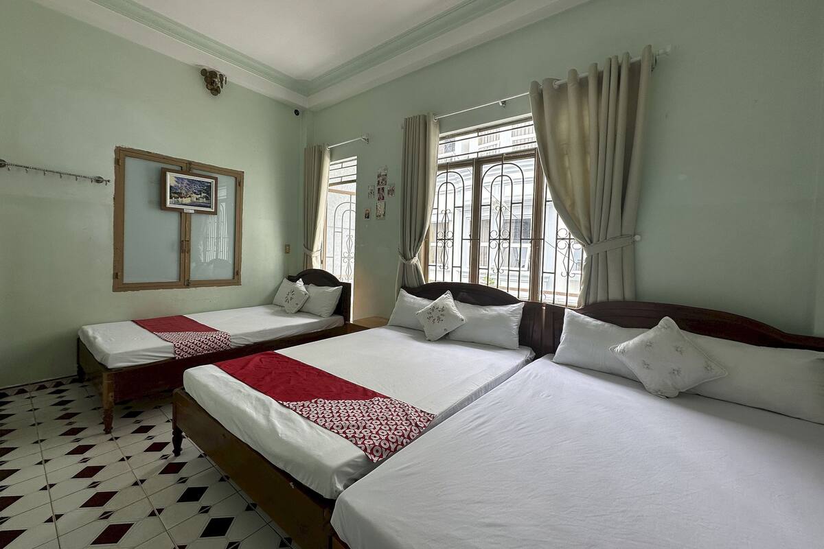 Une chambre avec deux lits, une fenêtre avec des rideaux, un miroir et un sol à motifs.