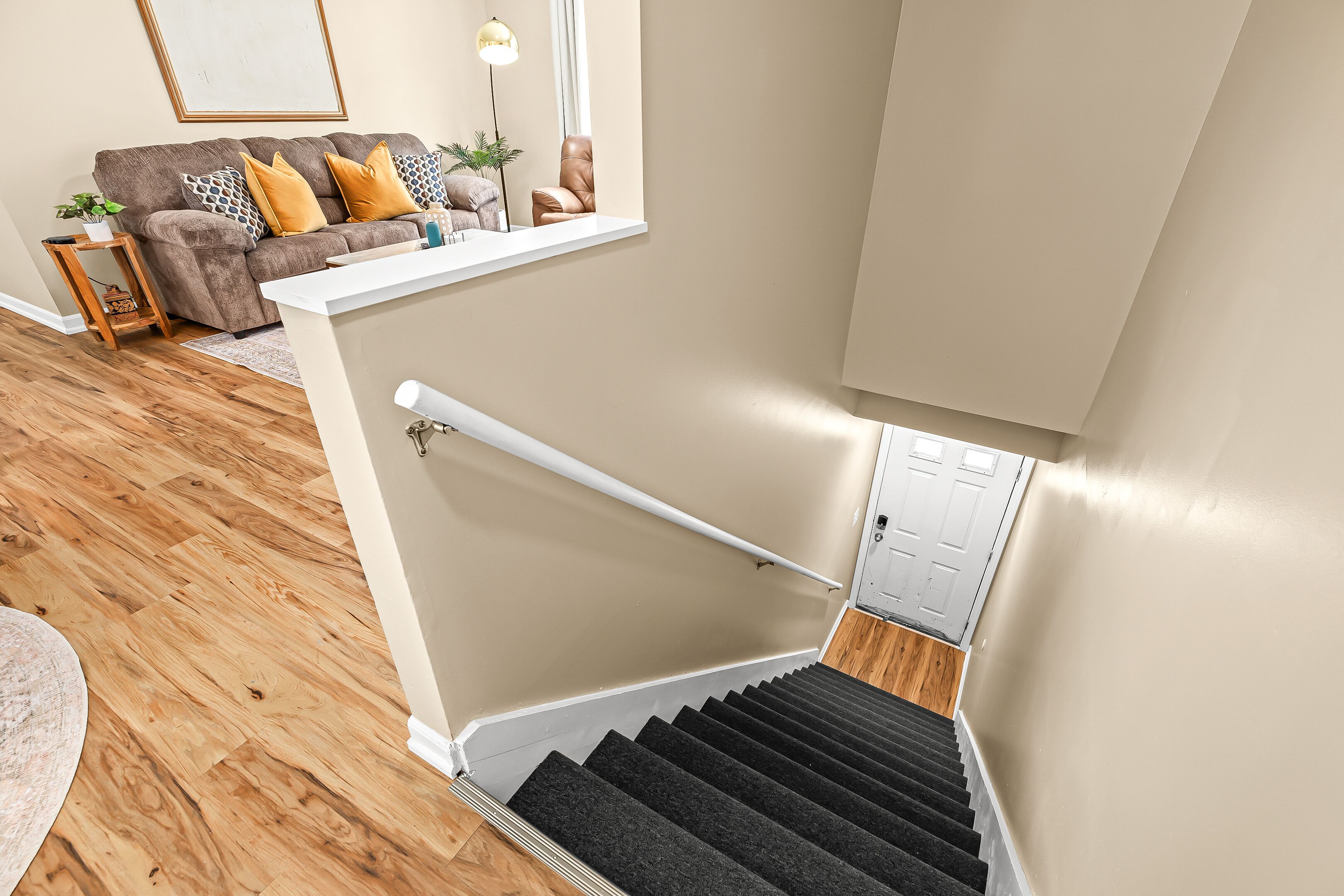 Un escalier avec une rampe, un plancher en bois et un mur de couleur beige.