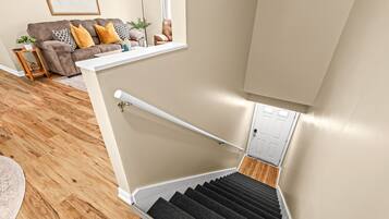 Un escalier avec une rampe, un plancher en bois et un mur de couleur beige.