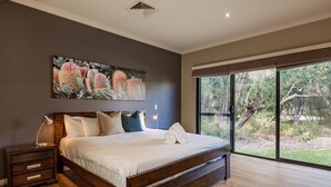 Een moderne slaapkamer met een groot bed, een nachtkastje, een wandlamp en een bloemschilderij.