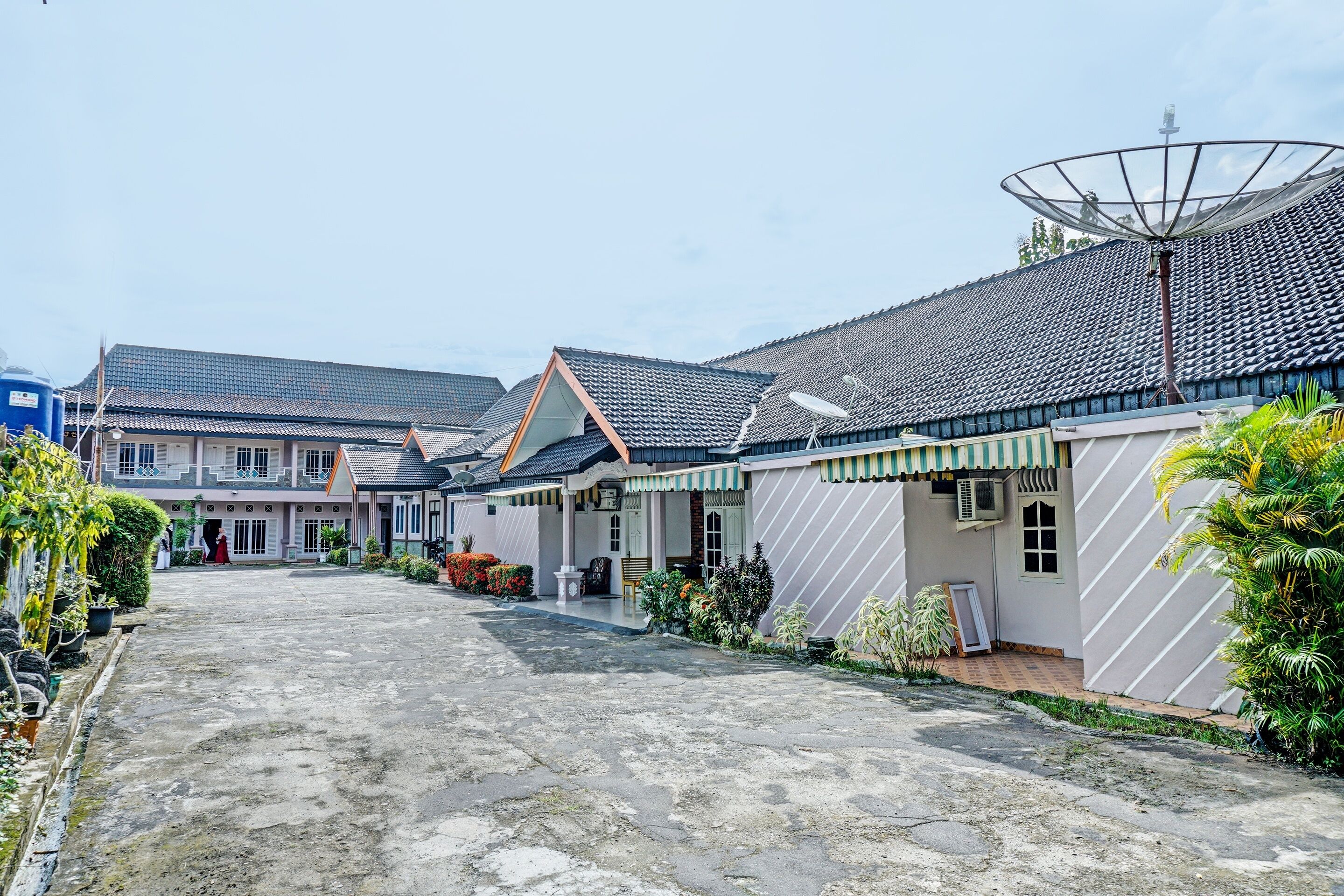A courtyard with traditional-style buildings, a satellite dish, and potted plants.