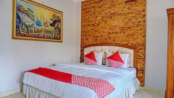Una habitación de hotel con cama, cabecera de madera, un cuadro en la pared y un armario.