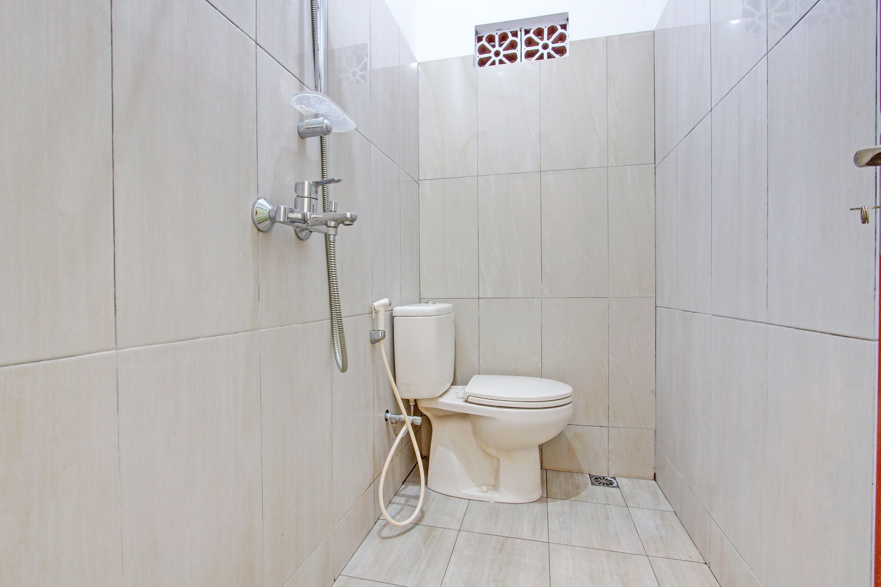 A small, modern bathroom with a toilet, a shower, and a toilet paper holder.
