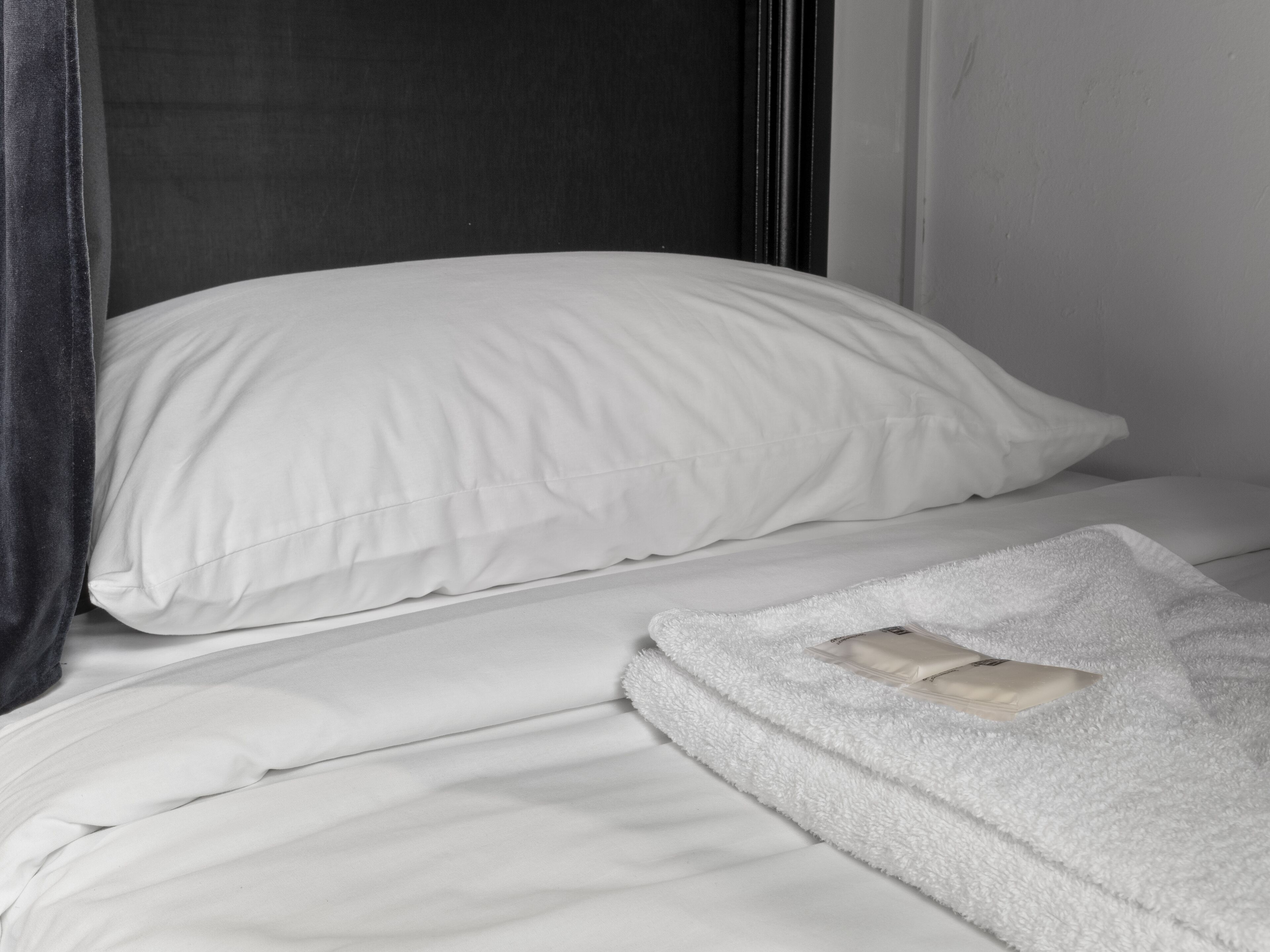 A bed with white bedding and a white blanket.