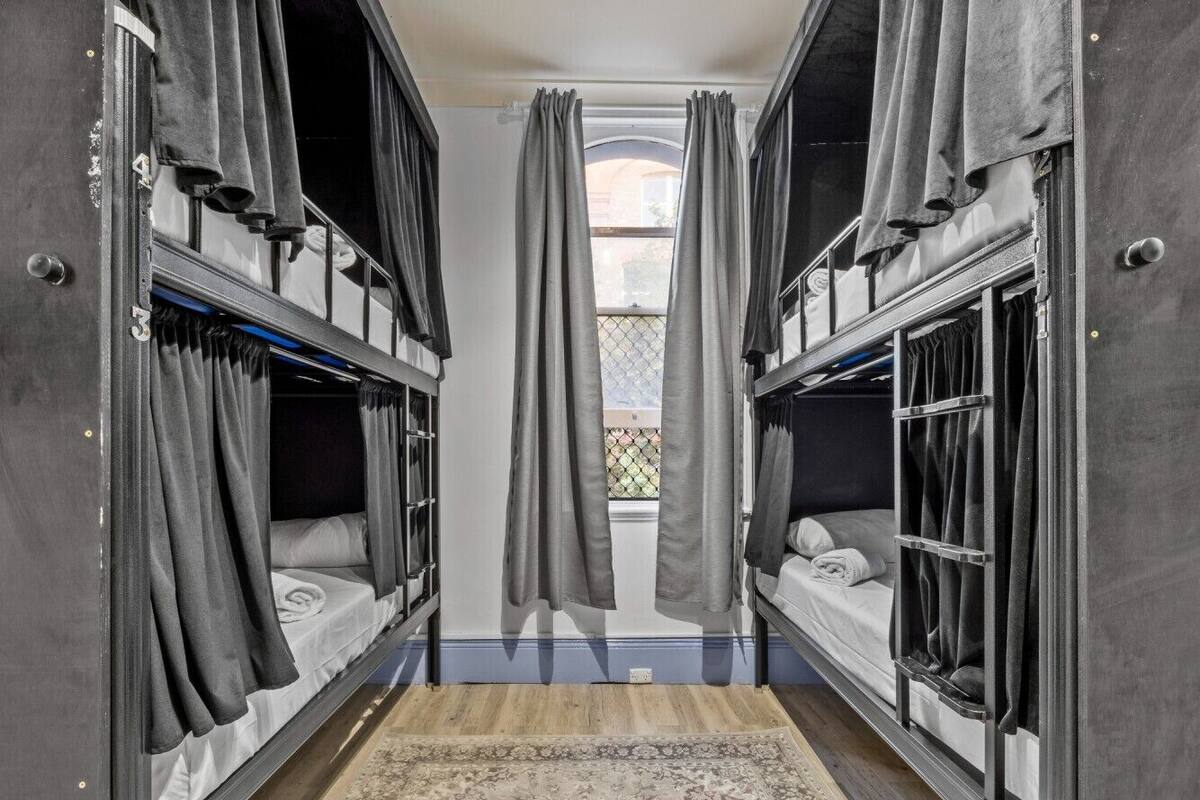 A room with bunk beds, a window with curtains, and a patterned rug.