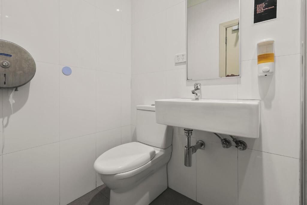 A small, clean bathroom with a toilet, sink, and mirror.