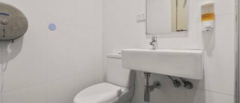 A small, clean bathroom with a toilet, sink, and mirror.