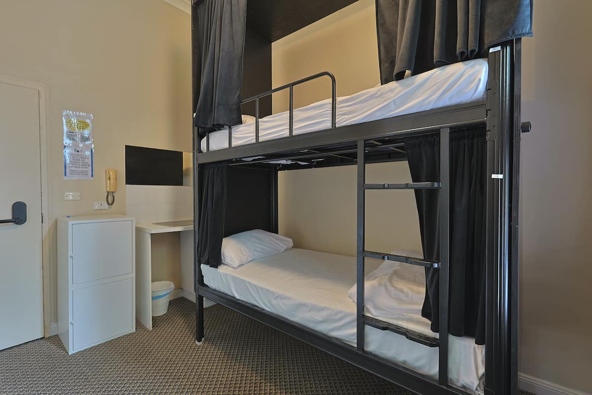 A bunk bed room with a desk and a small refrigerator.