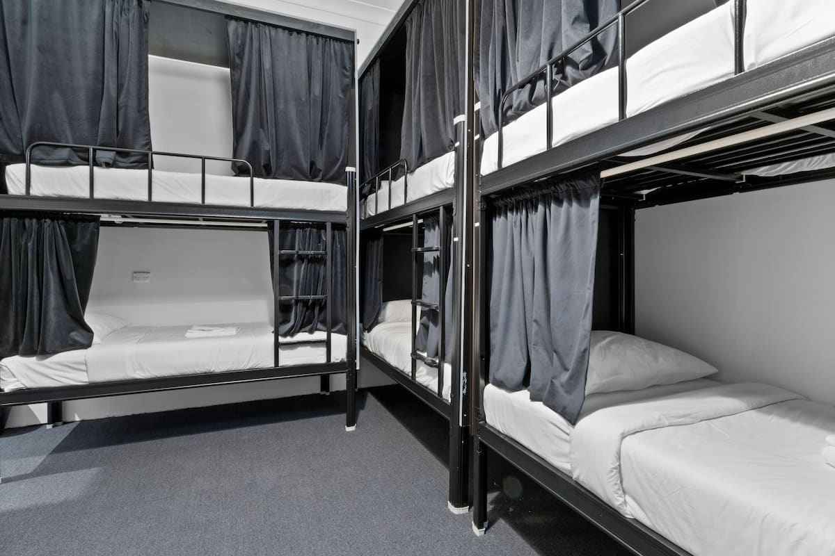A bunk bed room with curtains, a white wall, and a grey carpet.