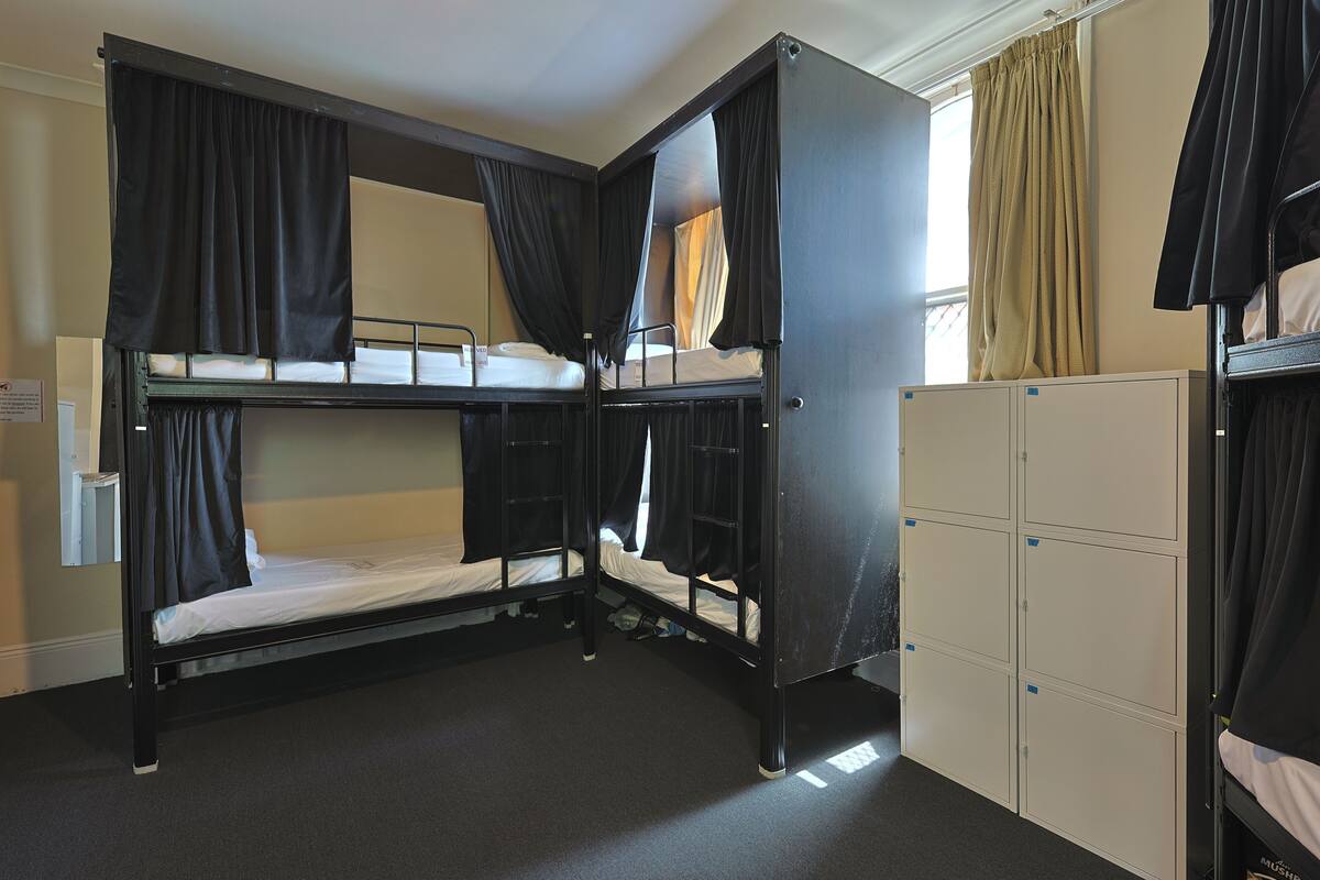 A bunk bed room with curtains, a window, and a wardrobe.