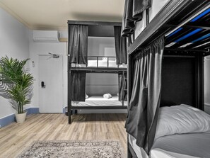 Habitación con literas, una planta en maceta, una puerta y un tapete estampado.