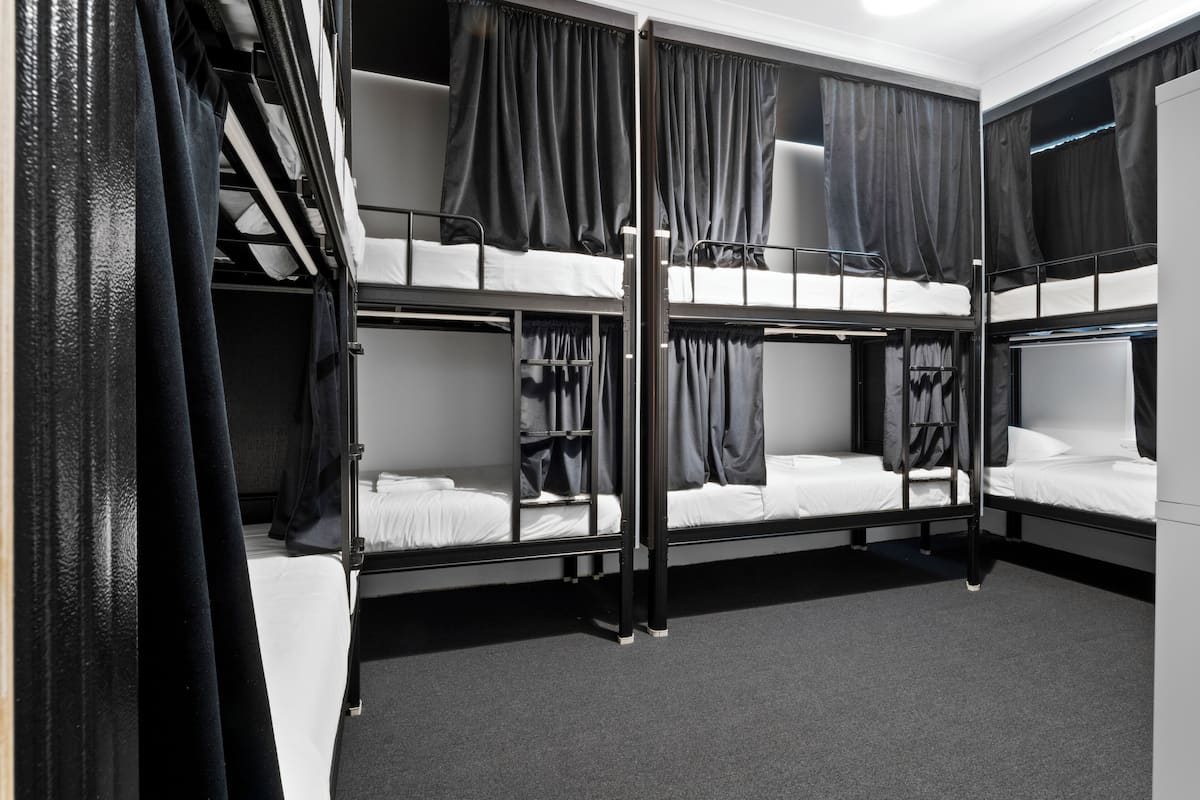 A bunk bed room with curtains, a wardrobe, and a carpeted floor.