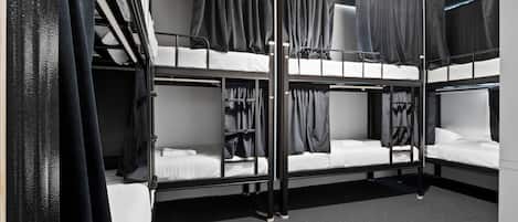 A bunk bed room with curtains, a wardrobe, and a carpeted floor.
