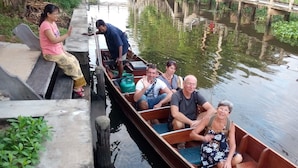 Un canal estrecho con una embarcación de madera que transporta pasajeros.