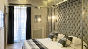 Une chambre moderne avec un grand lit, une cloison en verre et une tête de lit décorative.