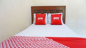 Een bed met twee rode kussens en een wit sprei met een rood-wit patroon.