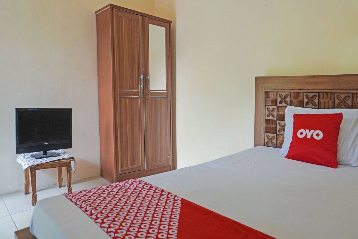 A hotel room with a bed, a television on a small table, and a wardrobe.