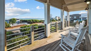 Überdachte Terrasse mit Blick auf das Meer und angrenzende Häuser.