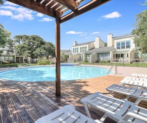 A wooden deck with a swimming pool, lounge chairs, and a covered area. - Tranquil Bay #50 (Rockport)