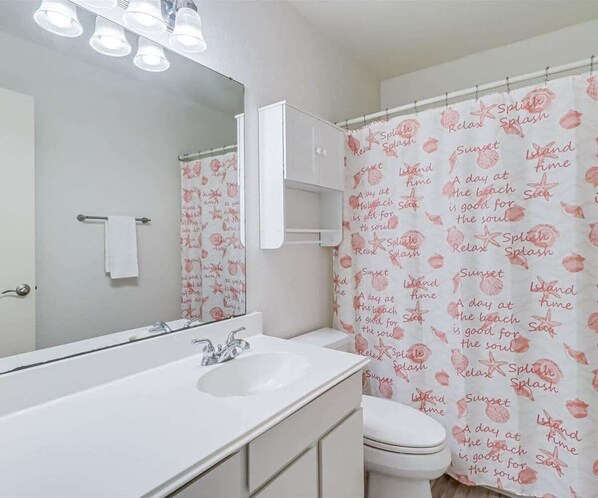 A bathroom with a white sink, mirror, and toilet.