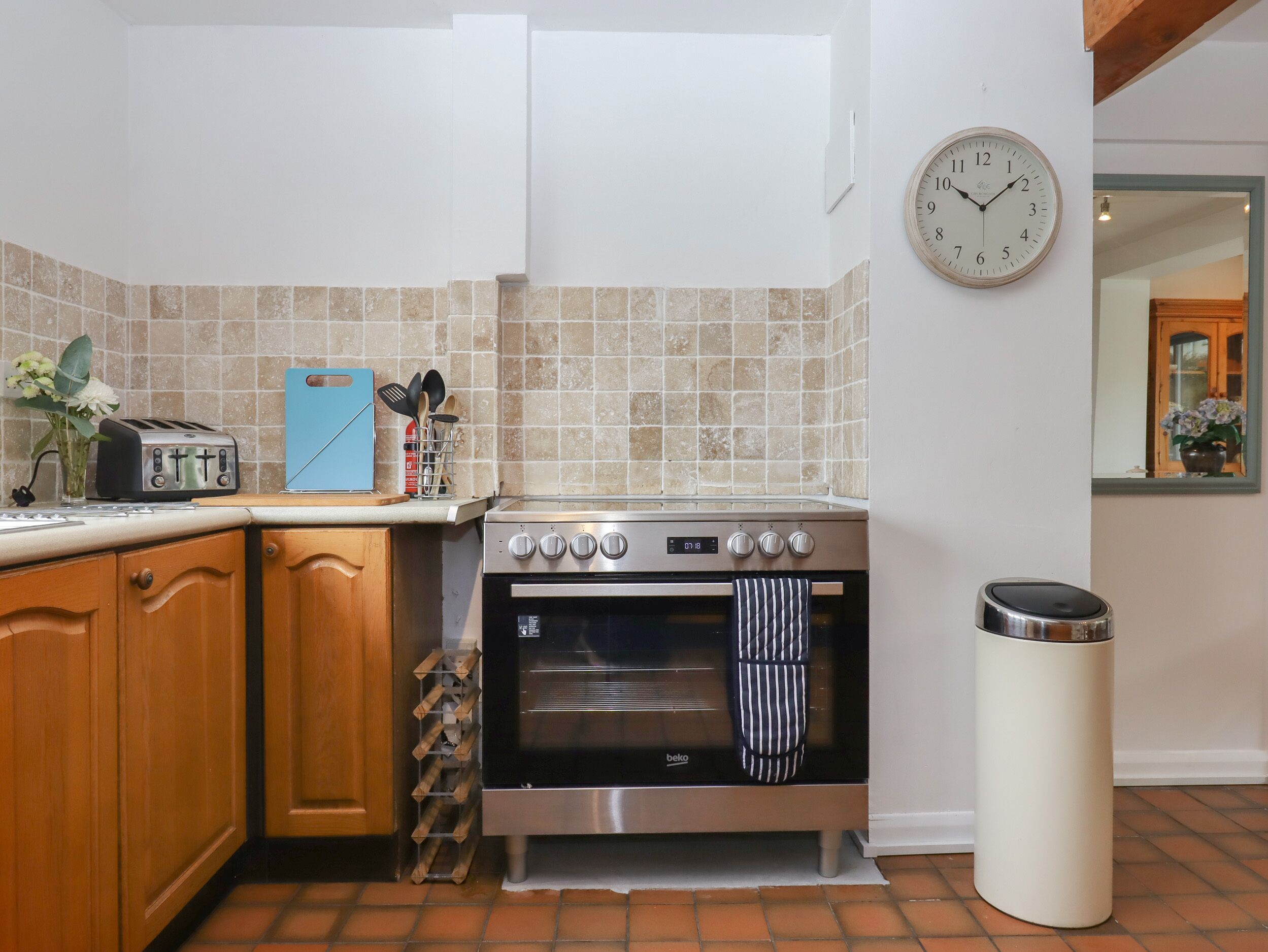 A kitchen with a stove, oven, and a trash can.
