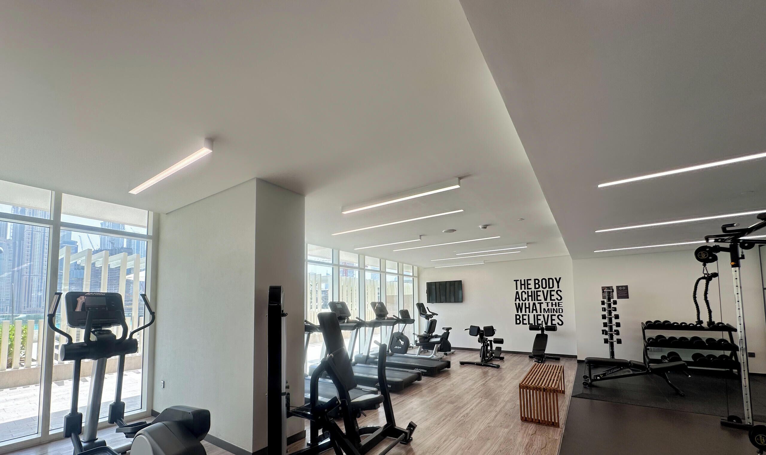 A modern gym with treadmills, elliptical machines, and free weights.