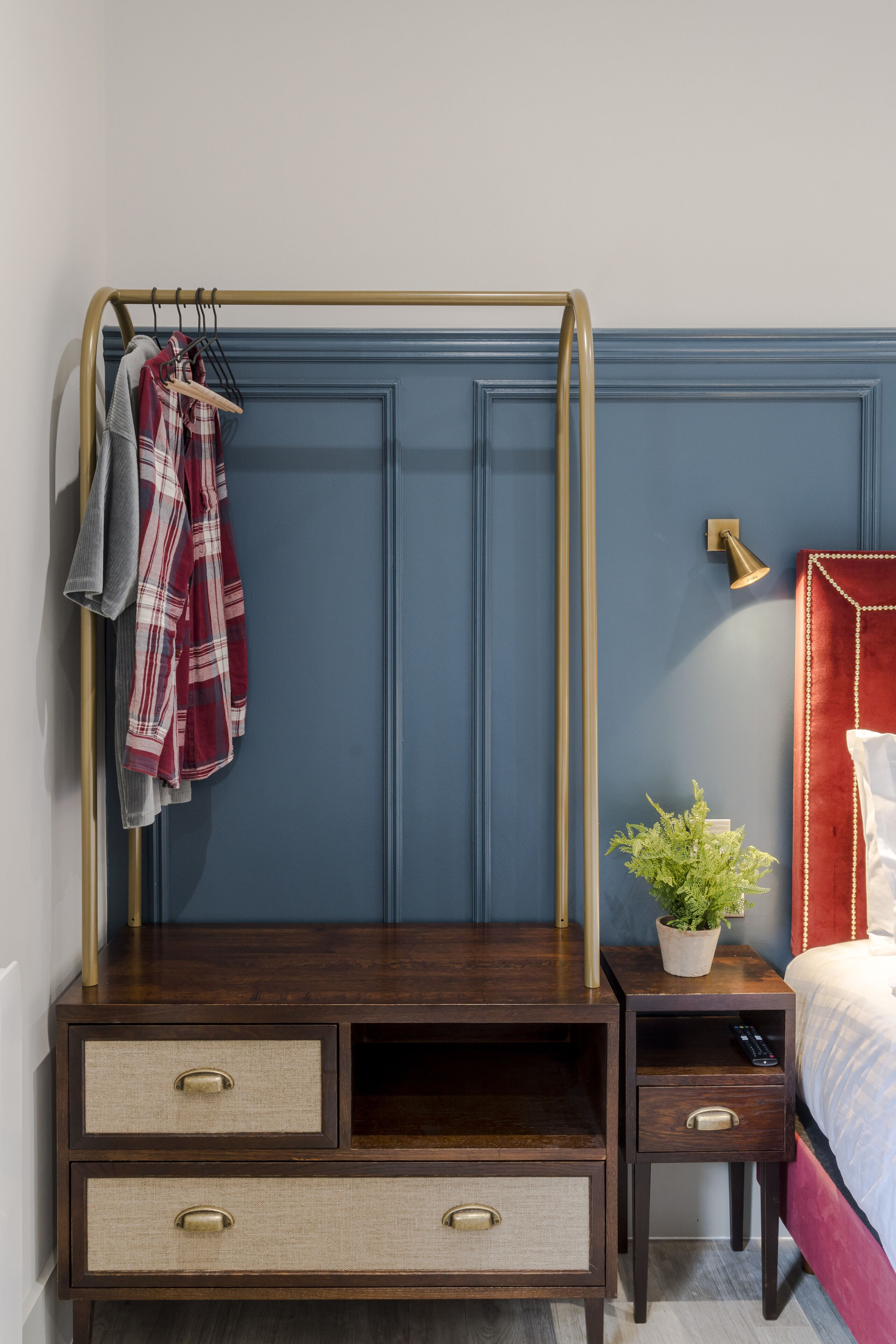 Quarto com cama, mesa de cabeceira, penteadeira e luminária na parede.