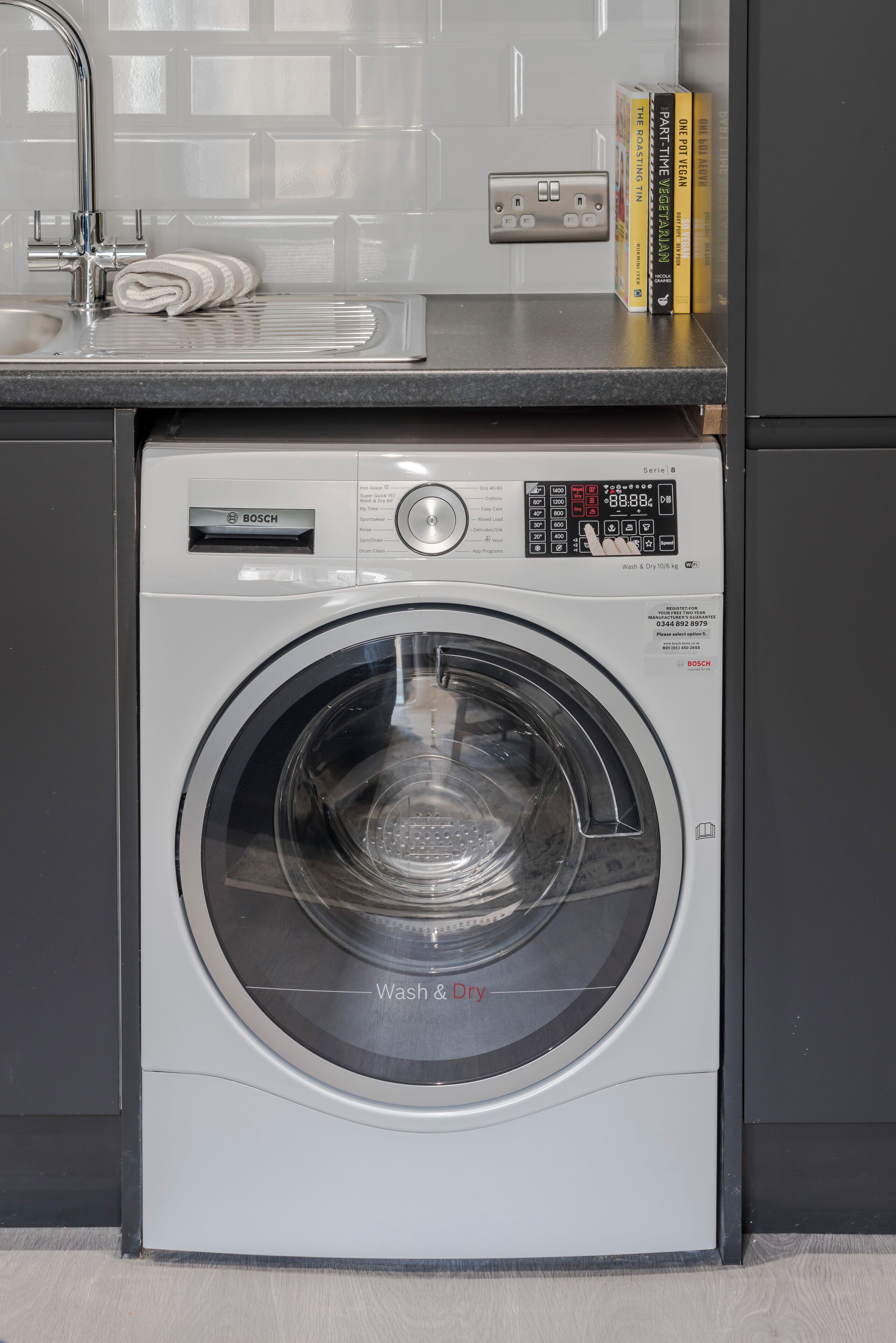 A Bosch washing machine in a modern kitchen with a sink and a countertop.