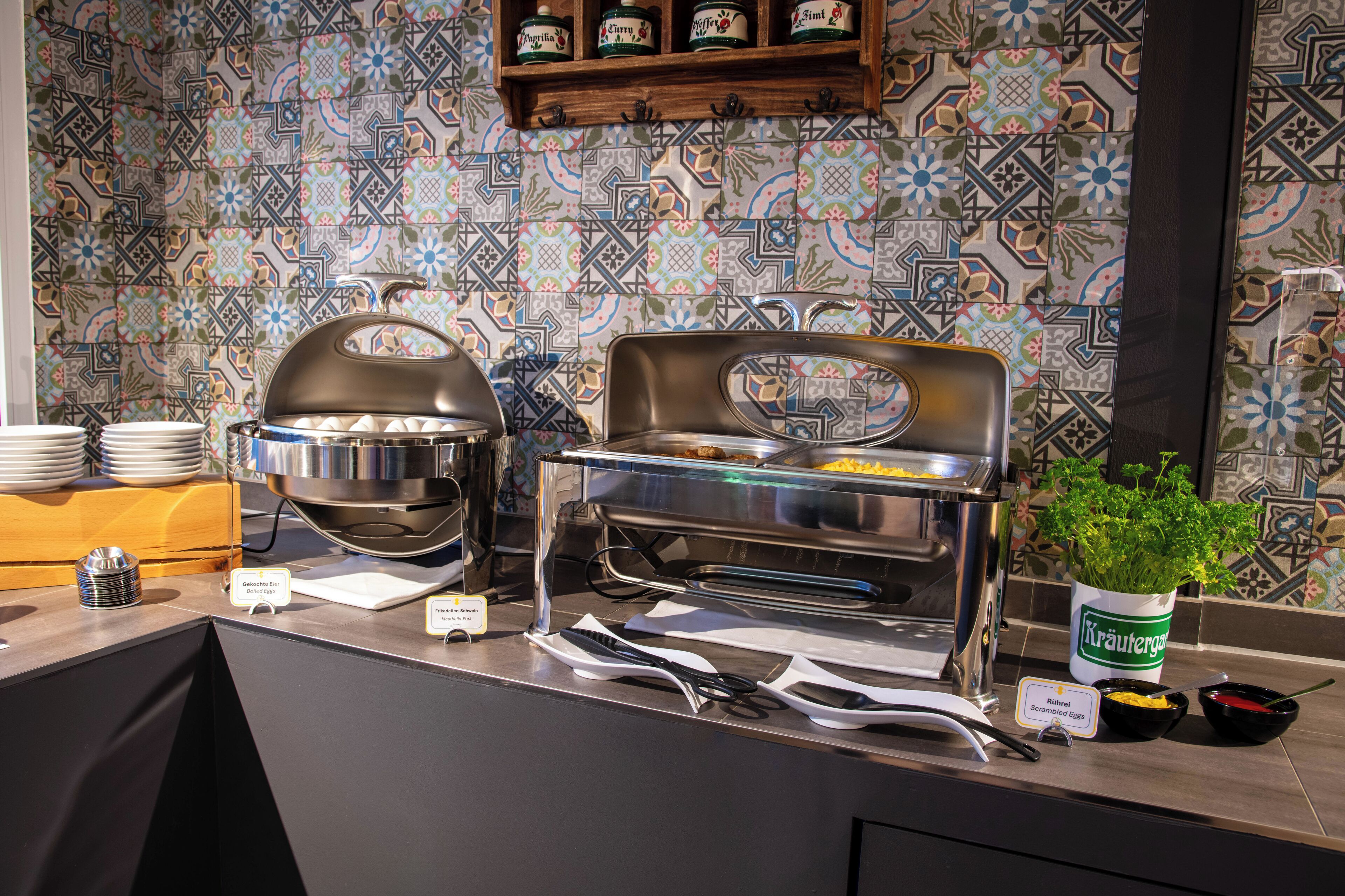 A buffet setup with multiple serving stations, including a covered egg station and a salad bar.