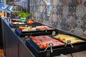 Un bufé con una variedad de alimentos, incluyendo carnes, quesos y verduras.