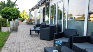An outdoor seating area with wicker furniture and potted plants. - [BEE]VILLAGE MESSEHOTEL HANNOVER-LAATZEN. (Laatzen)