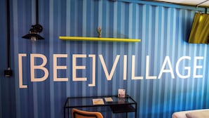 A room with a large wall sign reading "[BEE]VILLAGE". - [BEE]VILLAGE MESSEHOTEL HANNOVER-LAATZEN. (Laatzen)