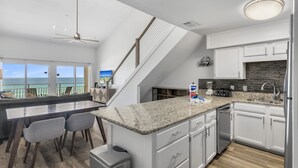 A modern kitchen with a granite countertop, white cabinets, and a view of the ocean. - Crystal Sands 314A - Gulf Front, Free Beach Service, Heated Pool, Sleeps 8 (Destin)