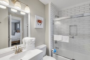 A bathroom with a white sink, a mirror with lights, a toilet, and a shower with a glass door. - Crystal Sands 314A - Gulf Front, Free Beach Service, Heated Pool, Sleeps 8 (Destin)