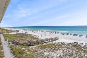 A beach with a wooden boardwalk leading to the shore, sandy beach, and clear blue water. - Crystal Sands 314A - Gulf Front, Free Beach Service, Heated Pool, Sleeps 8 (Destin)